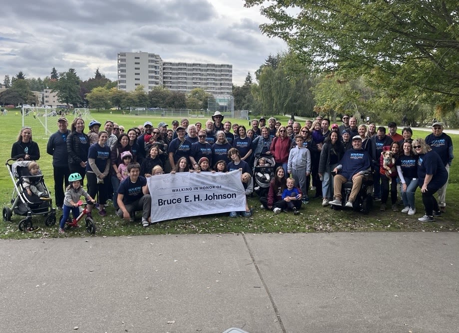 A big group of people holding a banner reading "Walking in honor of Bruce E.H. Johnson" at Seattle ALS Walk